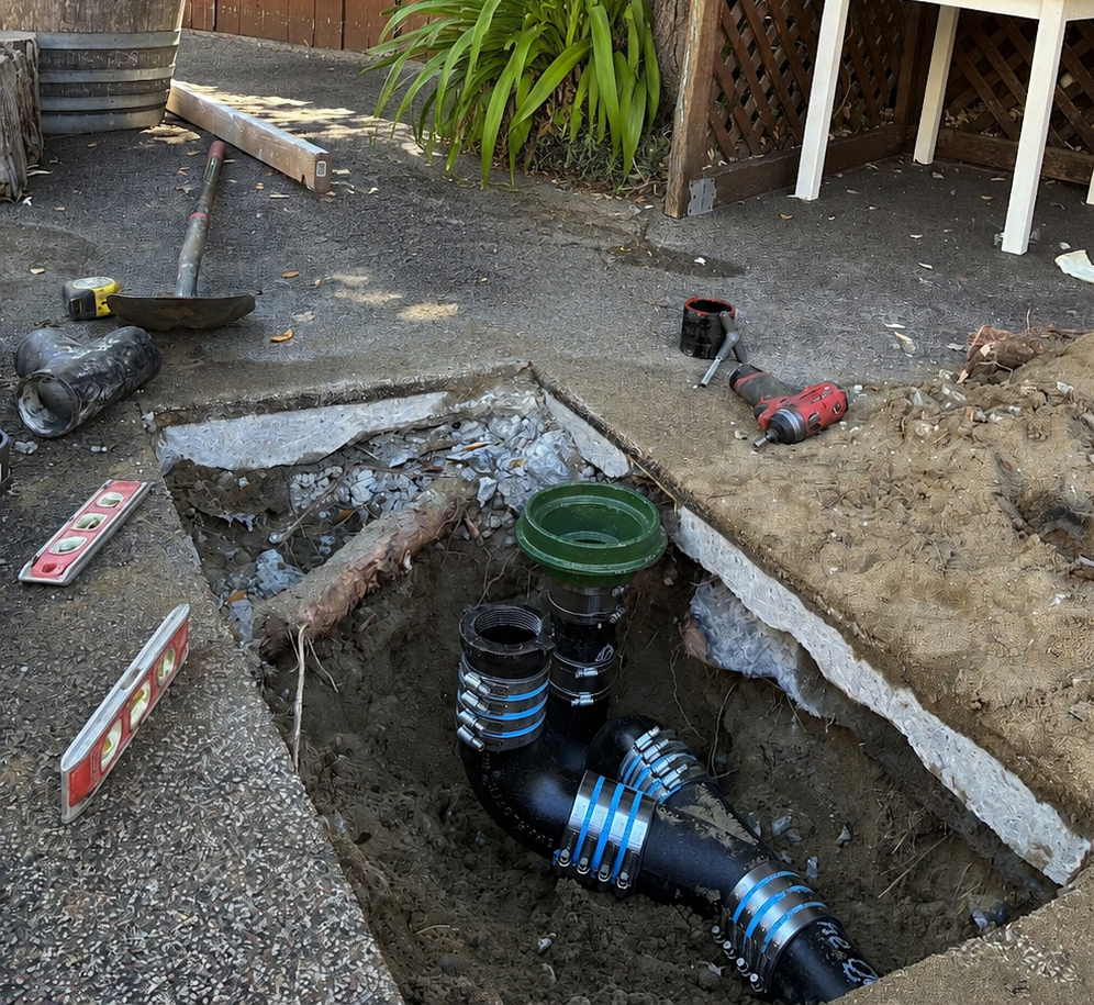 Open excavation with new black drain and cleanout piping